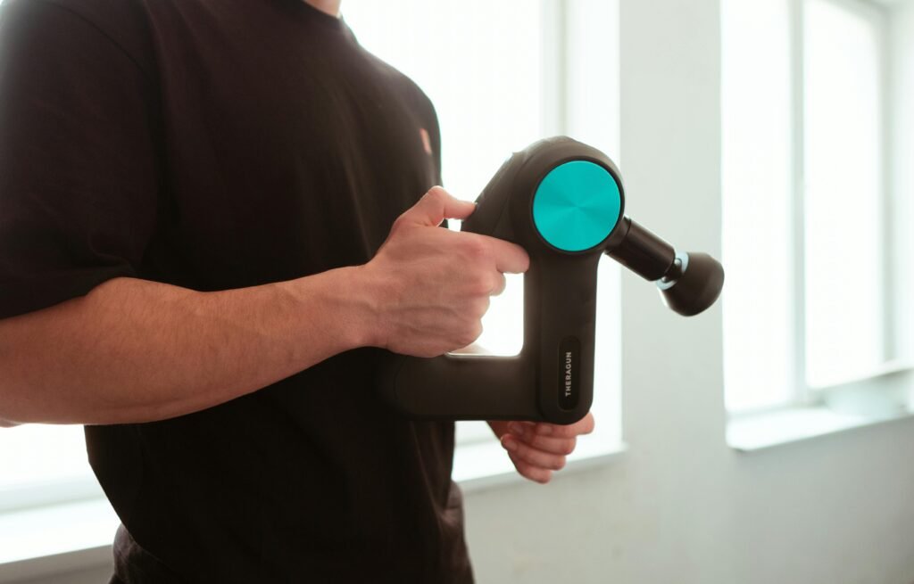 Close-up of a man using a massage device indoors with soft lighting.